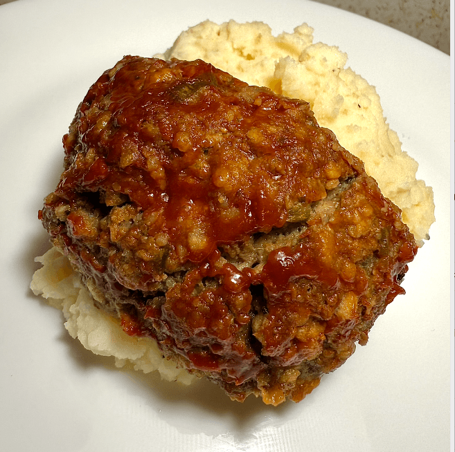 Easy gluten-free and low FODMAP meatloaf sliced and served on a plate with a side of vegetables.